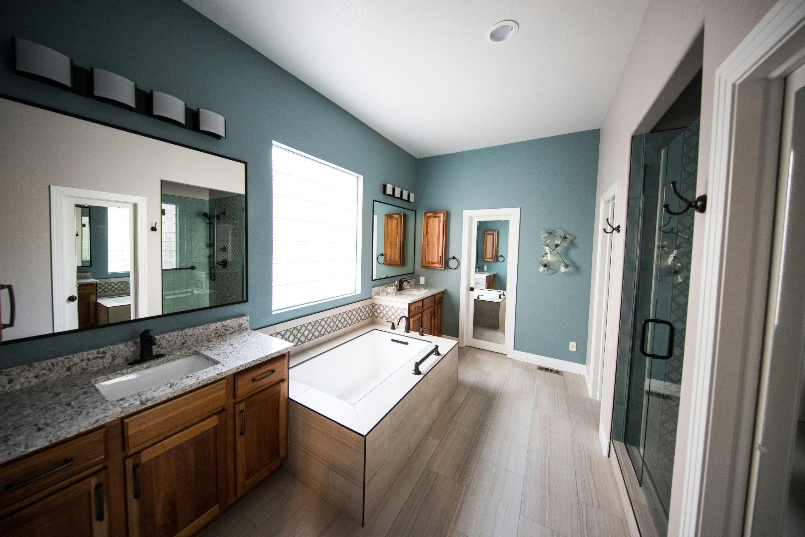 Services Spacious modern bathroom featuring a freestanding bathtub, wooden cabinets, and granite countertops.