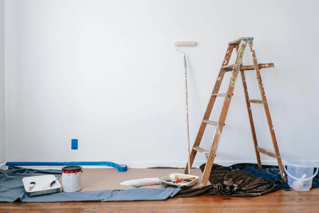 Services A room prepared for renovation with a ladder, paint supplies, and drop cloth.